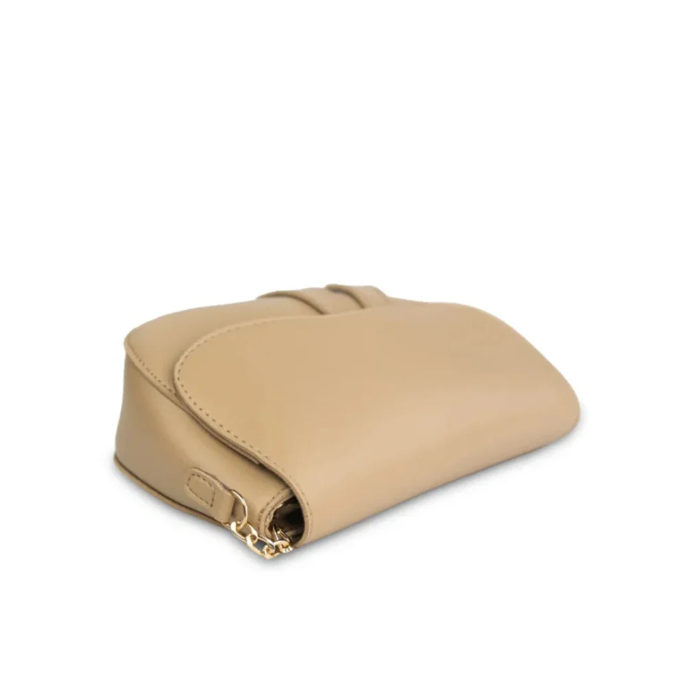 Nude beige crescent-shaped saddle bag with gold chain strap and smooth vegan leather finish.