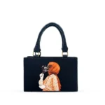 Black canvas tote bag featuring minimalist hijab girl illustration with floral accents and black leather handles.
