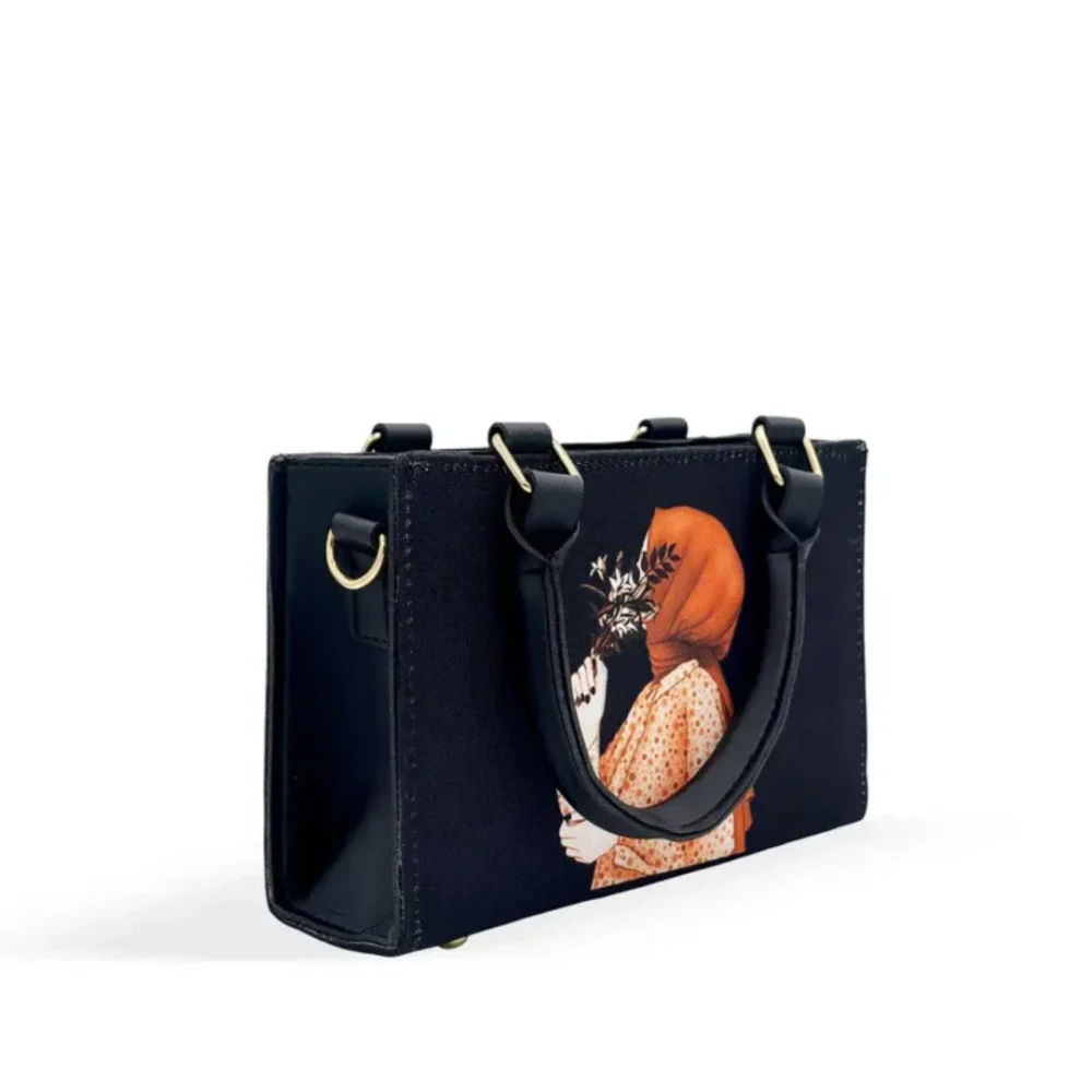 Black canvas tote bag featuring minimalist hijab girl illustration with floral accents and black leather handles