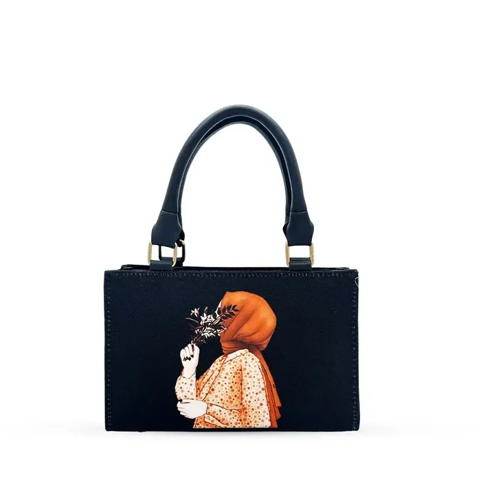 Black canvas tote bag featuring minimalist hijab girl illustration with floral accents and black leather handles.