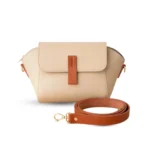 Beige pebbled vegan leather crossbody bag with a caramel brown magnetic flap detail and adjustable shoulder strap.