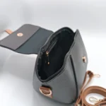 Black pebbled vegan leather crossbody bag with a caramel brown magnetic flap detail and adjustable shoulder strap.