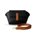 Black pebbled vegan leather crossbody bag with a caramel brown magnetic flap detail and adjustable shoulder strap.