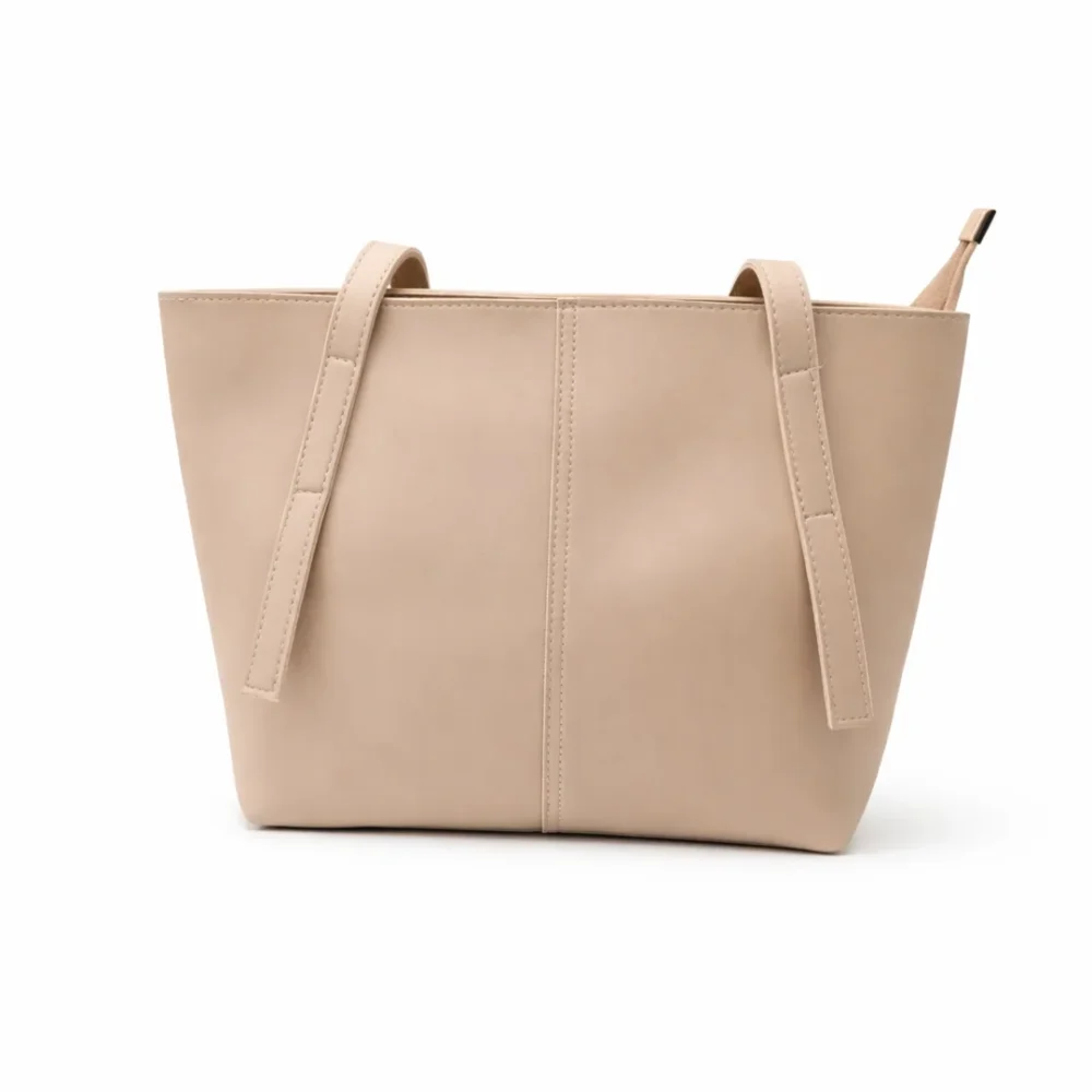 Front view of a soft nude beige minimalist tote bag with a central seam detail and long shoulder straps.