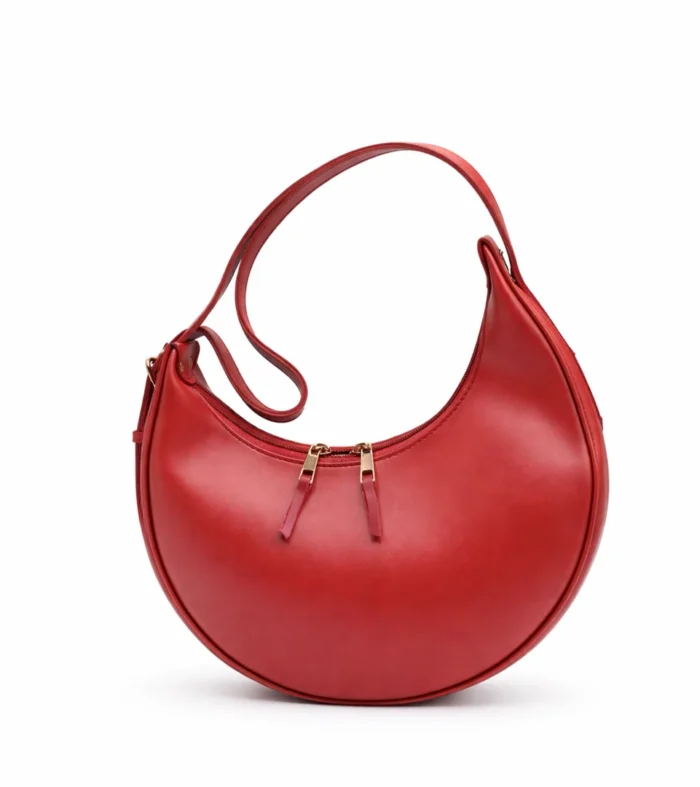 Side view of a smooth red crescent hobo bag with gold zippers and an integrated shoulder strap