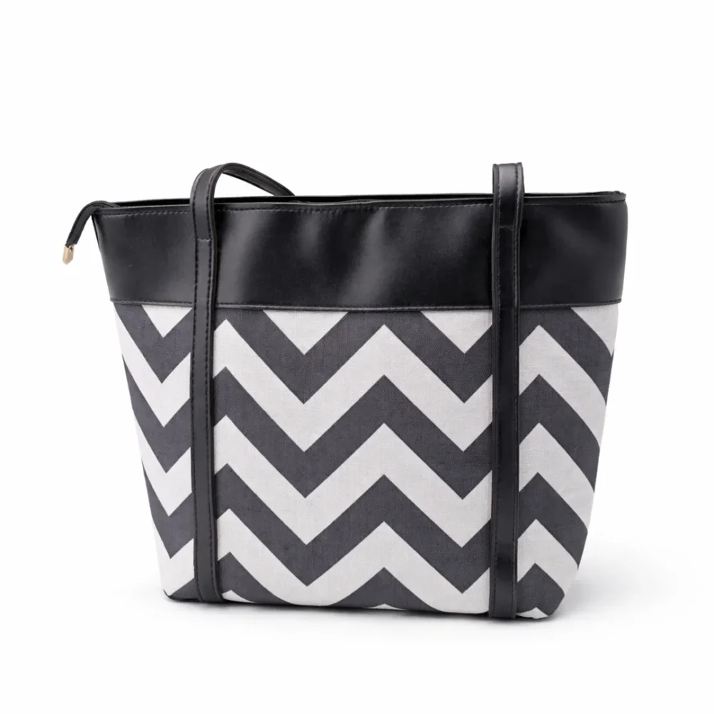 Large tote bag with a black and grey chevron pattern, black leather handles, and a secure top zipper.
