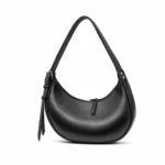 Side view of a smooth black crescent hobo bag with gold zippers and an integrated shoulder strap.